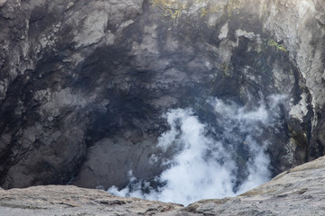 Closeup of the interior of Mount Bromo crater, East Java, Indonesia. White volcanic gas rising from below; yellow sulfur imbedded in the rock face in background.