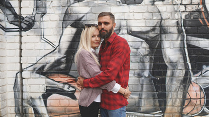 Fototapeta na wymiar Husband and wife hugging on grafitty background. Concept of seasoned love