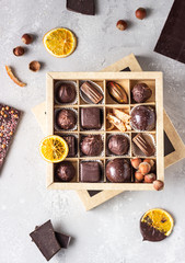 Assortment of sweet confectionery with chocolate candies and pralines in a gift box on a light grey stone background. Top view. 