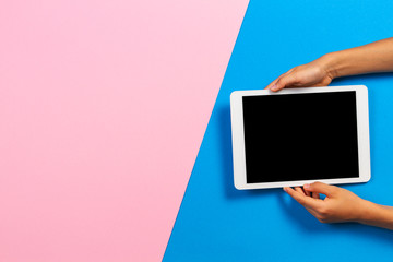 Kid hands with tablet computer on pastel pink and light blue background