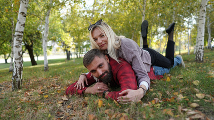 Husband and wife lying on ground in park among birch. Concept of seasoned love