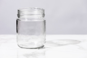 Empty glass jar on white marble surface.