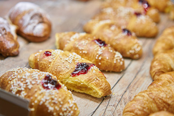 many of croissants with strawberry jam. Hot pastries lie on the showcase in the cafe. Buns and bagels in the store.