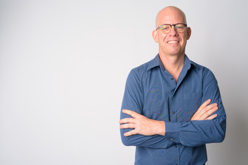Portrait of happy mature bald businessman smiling with arms crossed