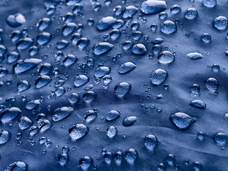 Waterproof blue fabric with raindrops. Blue background.