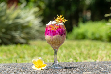 Fruit breakfast in a glass of oatmeal, red dragon fruit, passion fruit, mango and honey in nature background, closeup. The concept of healthy eating.