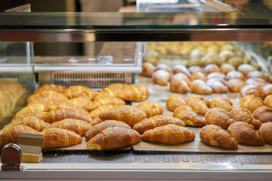 many of croissants. Hot pastries lie on the showcase in the cafe. Buns and bagels in the store.