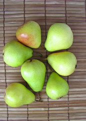 Group of ripe green pears on a wooden background. Autumn harvest of fruits. Flat lay, top view.