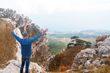 Traveler stands on a high mountain with his hands up. Crimea