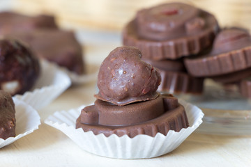 Close up homemade raw chocolate sweet candies with raspberries inside with droplets of water and raspberry juice on surface.
