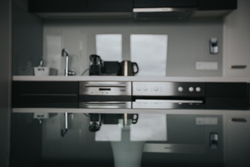 Interior of a kitchen. Focus in front on the glass table with blurred background. Natural light and desk space.