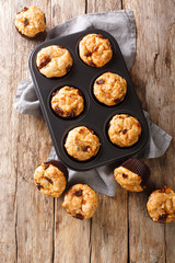 Mediterranean muffins with sun-dried tomatoes and cheddar cheese close-up in a baking dish. Vertical top view