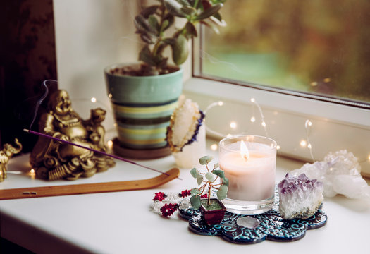 Feng Shui altar at home in living room or bed room. Attracting wealth and prosperity concept. Crystal clusters, wire tree with gemstones, golden smiling Buddha figure on table window sill.  - Powered by Adobe