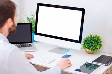 Young man working with computer with blank screen. Mock up design.