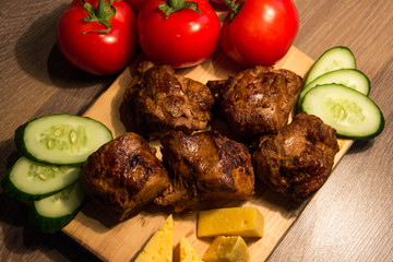 Shish kebab with cucumber and tomato on a wooden board