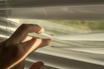 Someone opens the blinds part of the interior to look out the window