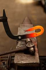 Perfect metal hook resting on anvil while being tapped.