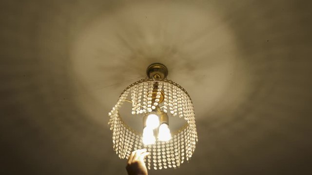 guy rotating antique chandelier decorative light and make shadow on the celling