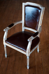 Beautiful leather armchair in retro style in studio is on wooden floor