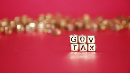 Gold beads with words 'TAX' on the pink background.