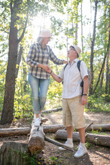 Couple of mature tourists wearing hats walking in the forest