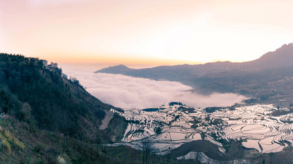 Small village and Terraced rice fields of YuanYang , China with sea of fog and cloud