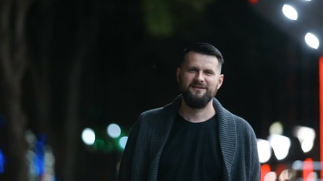 Close-up of a handsome bearded man happily sending a kiss and then leaving in the evening street