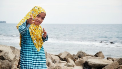 Portrait of young girl wearing hijab and malay traditional cloth "baju kurung" at the beach.