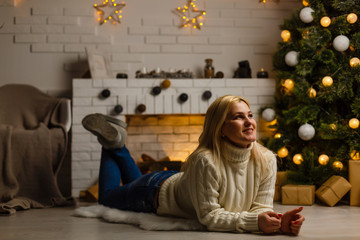 Excited woman on christmas lying on a couch in the living room at home