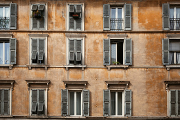 An orange exterior (facade) of a traditional Italian building with old wooden shutters on the windows in Brescia, Lombardy, Italy.  European architecture.