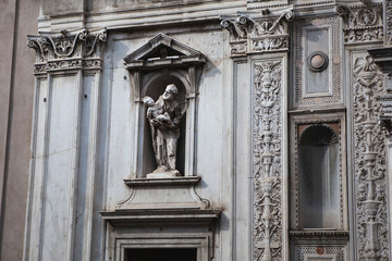 Obraz premium White marble cathedral with statues of old man and patterns on the building facade in the center of Brescia, Lombardy, Italy. Traditional Italian architecture with Roman elements, arches, columns.