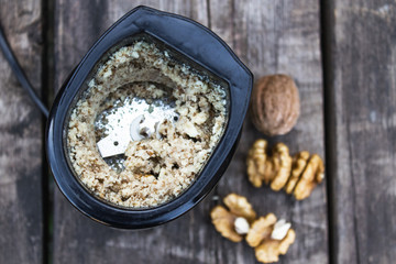 chopped walnut in a coffee grinder near the walnut kernel on an old wooden table.
