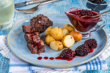 Pan-fried venison with blackberry sauce and boiled baby potatoes