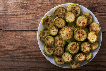 Fried zucchini slices with parsley on a white plate close up