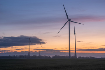 windmills on a field in Germany during a beautiful multicolored sunrise