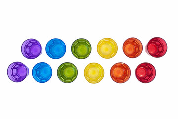 multi-colored glass on a white background. containers made of glass, ordered by the rainbow color...