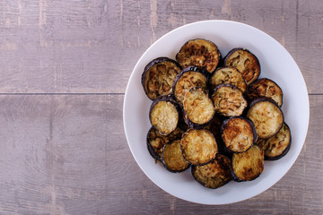 fried eggplant on the plate on rustic wooden background - top view. copyspase