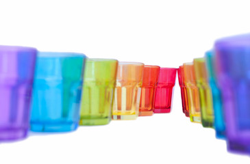 multi-colored glass on a white background. containers made of glass, ordered by the rainbow color spectrum, isolated, purple, blue, green, yellow, orange, red, with clipping path.