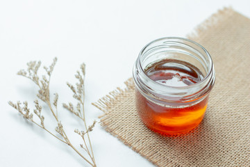 Honey in a pot or jar on white table background.