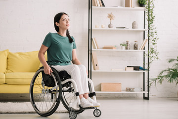 smiling disabled woman looking away while sitting in wheelchair at home - Powered by Adobe