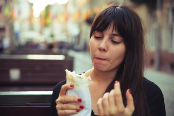 young smiling woman eating fast food outdoors