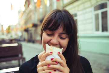 young smiling woman eating fast food outdoors