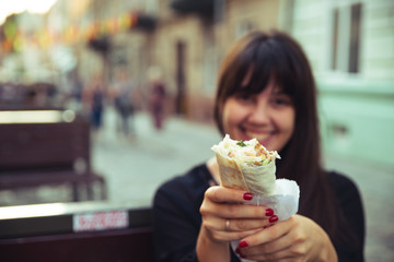 young smiling woman eating fast food outdoors