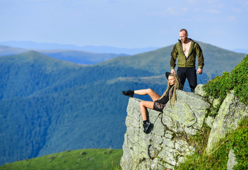 Couple hikers enjoy view. Hiking peaceful moment. Tourist hiker girl and man relaxing. Hiking benefits. Hiking weekend. On edge of world. Woman sit edge of cliff high mountains landscape background