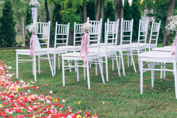 wedding or ceremony set up in garden, white chairs