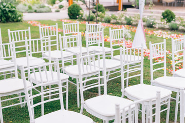 wedding or ceremony set up in garden, white chairs