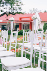 wedding or ceremony set up in garden, white chairs