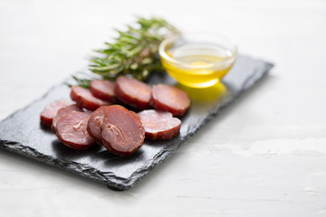 smoked portuguese sausage with olive oil and rosemary on black board