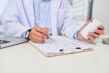 male doctor holding a box of pills in medical office