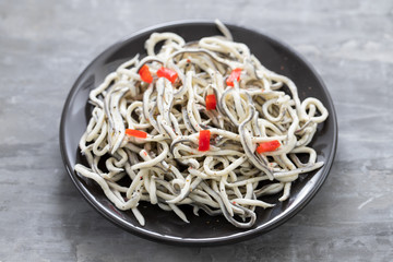 Traditional Spanish food. Gulas with oil on white plate.